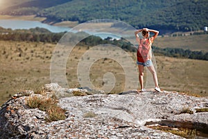 Woman standing at edge of cliff, enjoying breathtaking view. Vacation time. World travel. Adventure trip to mountains.