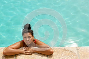 Woman standing at the edge of swimming pool in the backyard at home