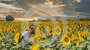 Woman standing in field surrounded by sunflowers at sunset