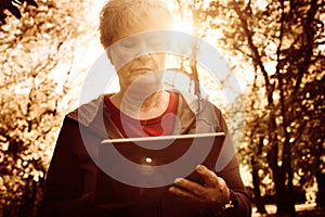 Woman standing in forest and typing on iPod.