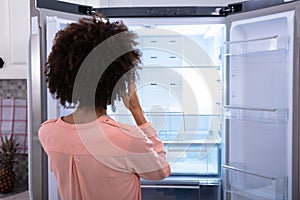 Woman Standing In Front Of Empty Refrigerator