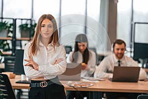 Woman is standing in front of her colleagues. Business people in formal clothes are working in the office together