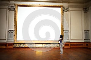 Woman standing in front of and looking at big blank painting canvas with huge frame