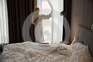 Woman standing in front of window in bedchamber after morning awakening