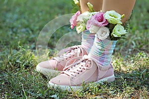 Woman standing on green grass with flowers in socks, closeup