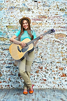 Woman standing with guitar against grunge wall