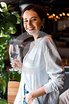 Woman standing with hand in pocket while holding glass with red wine