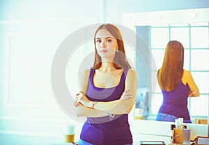 Woman standing with hands folded in her salon