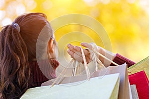 A woman standing with her back and holding the colorful packages .