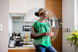 Woman standing in her kitchen drinking coffee