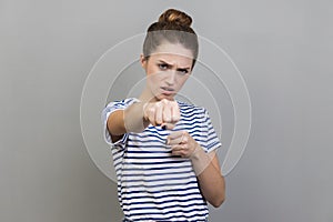 Woman standing holding clenched fists up ready to boxing, fighting spirit, boxing.