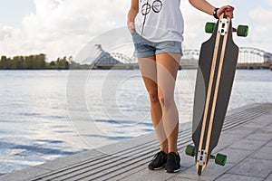 Woman standing and holding longboard