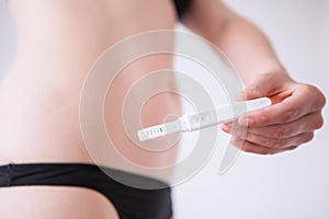 Woman standing and holding a pregnancy test