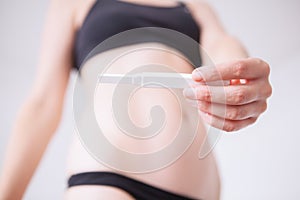 Woman standing and holding a pregnancy test