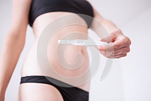 Woman standing and holding a pregnancy test