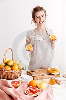 Woman standing indoors and holding citruses in hands