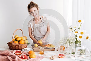 Woman standing indoors and squeezes out juice of a citruses