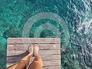 Woman standing on the jetty with beautiful clear water from the surface in Mabul Island, Semporna. Tawau, Sabah. Malaysia.