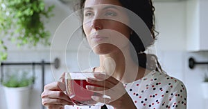 Woman standing in kitchen drinking hot fresh brewed black tea