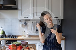 Woman standing in kitchen reading great sms news feels happy