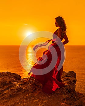 A woman is standing in a long red dress, a fashion model in an evening dress, soaring over the sea