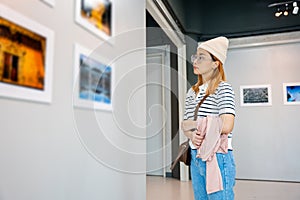 Woman standing she looking art gallery collection in front framed paintings pictures