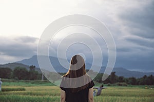 A woman standing and looking at a beautiful rice field onward with feeling relaxed