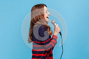 Woman standing with microphone, singing her favorite songs in karaoke, talented singer performing.