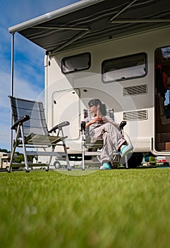 Woman is standing with a mug of coffee near the camper RV.