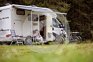 Woman is standing with a mug of coffee near the camper RV.