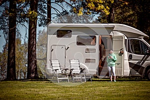 Woman is standing with a mug of coffee near the camper RV.