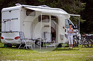 Woman is standing with a mug of coffee near the camper RV.