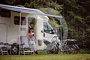 Woman is standing with a mug of coffee near the camper RV.