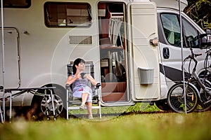 Woman is standing with a mug of coffee near the camper RV.