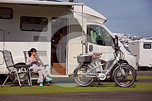 Woman is standing with a mug of coffee near the camper RV.