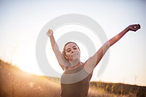 Woman standing in the nature with closed eyes and outstretched arms