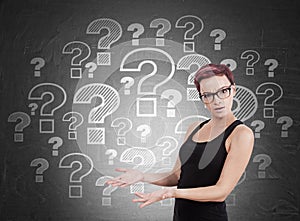 Woman standing near blackboard with question marks