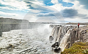 Woman standing near famous Selfoss waterfall in Vatnajokull National Park, Northeast Iceland photo