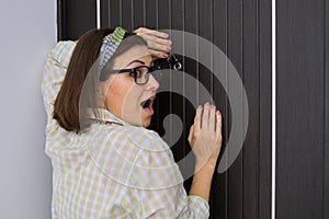Woman standing near front door looking through the peephole