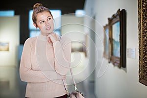 Woman standing near painting in art museum