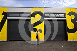 Woman standing  near wall with numbers one, two,three
