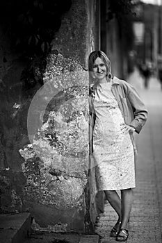 Woman standing near a wall in the street. Black and white photo.