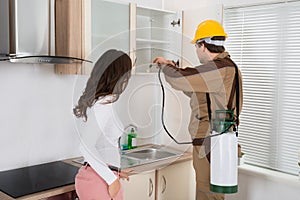 Woman Standing Near The Worker Spraying Pesticide On Shelf