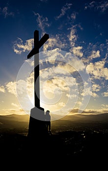 Woman standing next to cross at sunset in Bray Head, Ireland