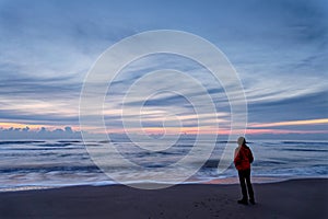 A woman standing by the ocean after sunset. Long exposure. North Holland dune reserve, Egmond aan Zee, Netherlands