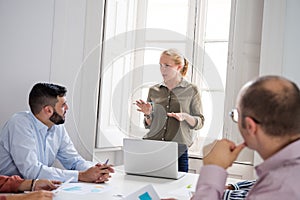 Woman standing in an office chairing a meeting