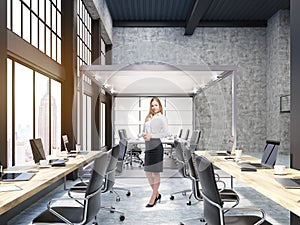 Woman standing in open office with glass board room in New York