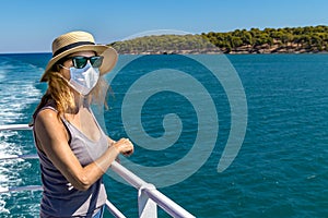 Woman standing outdoors on ferry ship with a surgical mask during Covid-19 travelling in Greece