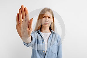 Woman standing with outstretched hand showing stop gesture on white background