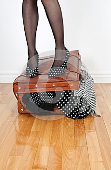 Woman standing on overfilled suitcase